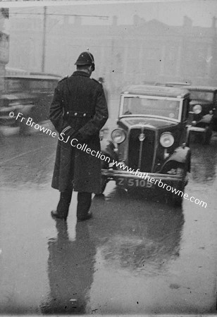 GARDA IN DOWNPOUR COLLEGE GREEEN WITH TCD IN BACKGROUND